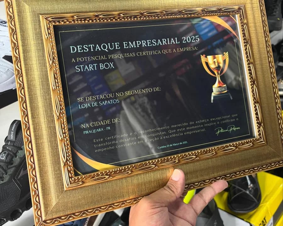A placa dourada do Destaque Empresarial 2025, com o nome Start Box, o segmento loja de sapatos e a cidade de Piraquara, PR